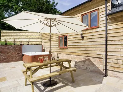 a picnic table with an umbrella next to a tub at Cefnaire Isaf in Newtown
