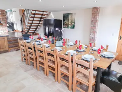 a dining room with a wooden table and chairs at Cefnaire Isaf in Newtown