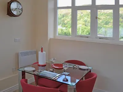 a dining room with a glass table and red chairs at Porter's Lodge in Glyn-Dyfrdwy