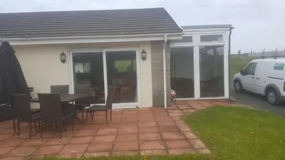 a house with a patio with a table and chairs at Aberceiro Bungalow in Aberystwyth