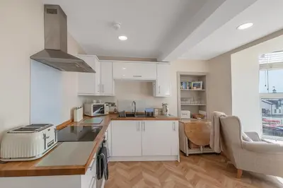 a kitchen with white cabinets and a counter top at Popular Sea View Apartment in Aberdyfi