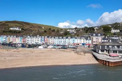 a beach with a bunch of houses on a hill at Popular Sea View Apartment in Aberdyfi