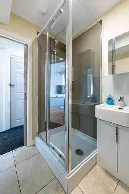 a glass shower in a bathroom with a sink at Popular Sea View Apartment in Aberdyfi