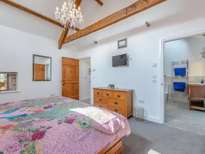 a bedroom with a bed and a dresser and a mirror at West Barn in Llansadwrn