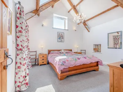 a bedroom with a bed in a room with wooden ceilings at West Barn in Llansadwrn