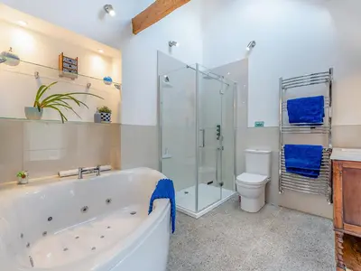 a bathroom with a tub and a shower and a toilet at West Barn in Llansadwrn