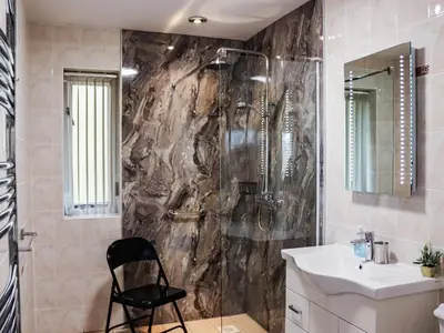 a bathroom with a shower and a black chair at Arenig - Uk48508 in Bala