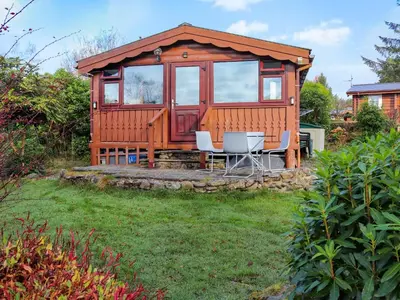 a cabin with a table and chairs in a yard at Babbling Brook Lodge in Trawsfynydd