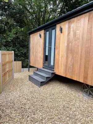 a tiny house with a door and a set of stairs at Newydd Lodge with private hot tub in Llangollen