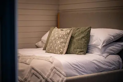 a bed with three pillows on top of it at Dinas Lodge with private hot tub in Llangollen