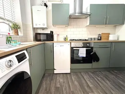 a kitchen with green cabinets and a dishwasher at Shrewsbury Stayscape - Modern & Spacious 3BR - Family & Business Ready for 7 by Parydise Properties in Bicton