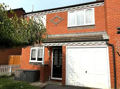 a red brick house with a large white garage at Shrewsbury Stayscape - Modern & Spacious 3BR - Family & Business Ready for 7 by Parydise Properties in Bicton