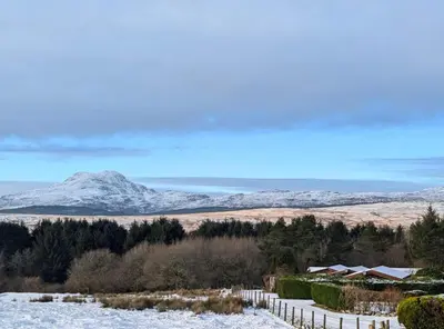 a snowy field with snow covered mountains in the background at Thistledonia in Trawsfynydd