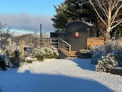a small shed with a wooden ramp in the snow at Ty'r Bugail - Shepherds Hut in Llanddwywe