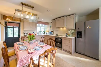 a kitchen with a table with a pink table cloth at The Garden Cottage in Craven Arms