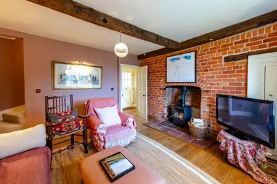 a living room with a brick fireplace and a tv at The Garden Cottage in Craven Arms