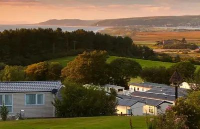 a group of houses on a hill next to a lake at 3 Bed Caravan - Sleeps 6 - Pets - Parking - Wifi in Borth