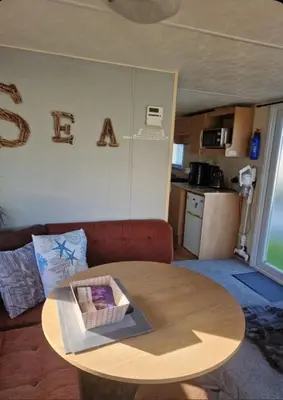 a living room with a table and a couch at 3 Bed Caravan - Sleeps 6 - Pets - Parking - Wifi in Borth