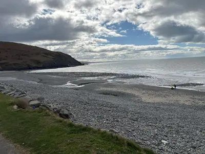a beach with a person standing on the shore at The Perfect Escape 2 Bedroom Static Caravan Pet Friendly in Aberystwyth