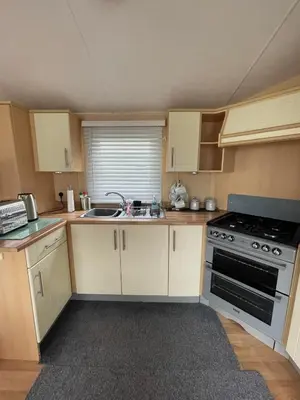 a small kitchen with a stove and a sink at The Perfect Escape 2 Bedroom Static Caravan Pet Friendly in Aberystwyth