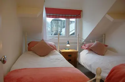 two beds in a small room with a window at Cysgod Idris Cottage in Dolgellau