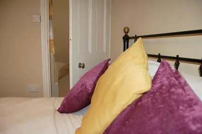 a bed with purple and yellow pillows on it at Cysgod Idris Cottage in Dolgellau