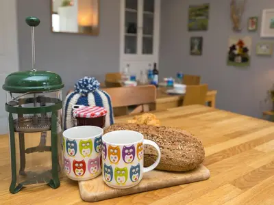 two coffee cups and a loaf of bread on a table at Colourful homely 2 bed terrace - Pass the Keys in Shrewsbury