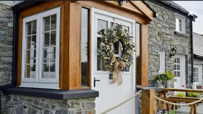 a cottage with a white door and a window at Golygfar Mynydd in Ystrad Meurig