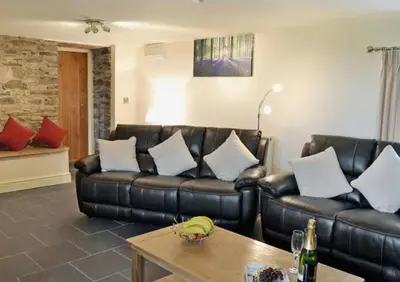 a living room with a leather couch and a table at Golygfar Mynydd in Ystrad Meurig