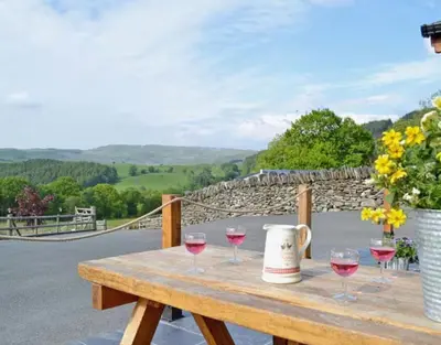 a wooden table with glasses of wine on it at Golygfar Mynydd in Ystrad Meurig