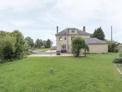a large house with a grassy yard with a yard at Tan Y Fron in Dyffryn