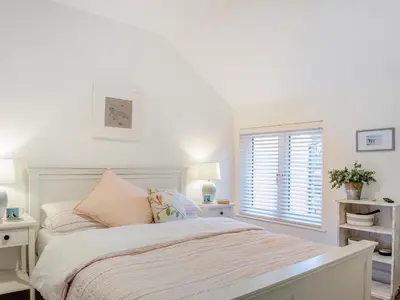 a white bedroom with a bed and a window at Isfryn in Llanbedr