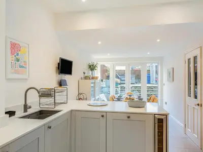a kitchen with white cabinets and a sink and a window at Isfryn in Llanbedr