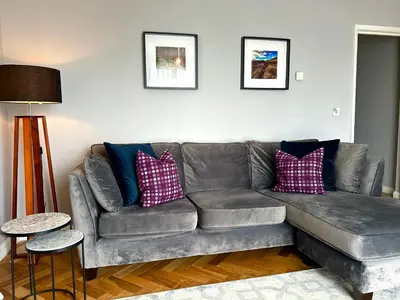 a living room with a gray couch with pillows at Luxury 2 bedroom town apartment in Aberystwyth