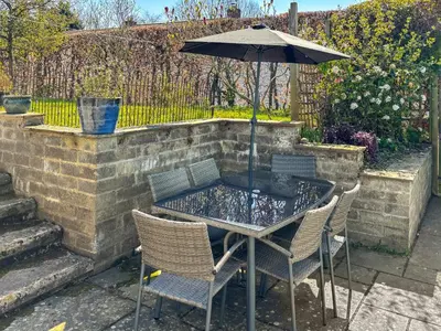 a table with chairs and an umbrella on a patio at Sheldon Cottage in Bishops Castle
