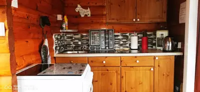 a kitchen with wooden cabinets and a stove top oven at Hamishs log cabin in Trawsfynydd