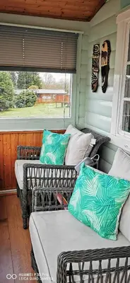a porch with two wicker chairs and a window at Hamishs log cabin in Trawsfynydd