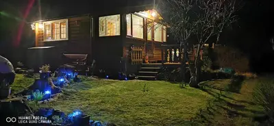a house with blue lights in the yard at night at Hamishs log cabin in Trawsfynydd