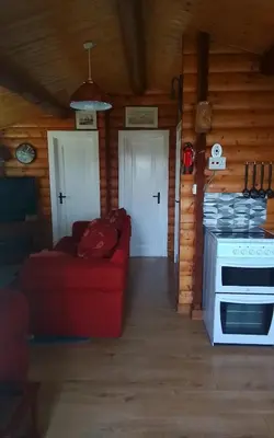 a living room with a red couch and a stove at Hamishs log cabin in Trawsfynydd