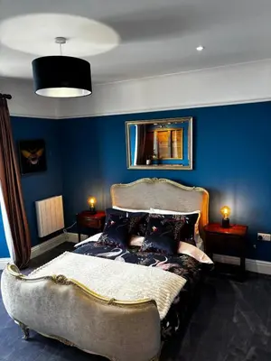 a bedroom with a bed with a blue wall at Stunning fully refurbished house in New Quay