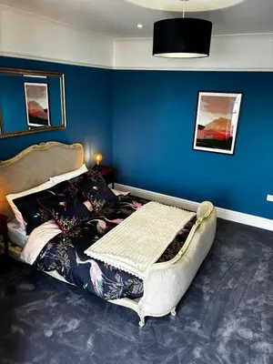 a bedroom with a bed with a blue wall at Stunning fully refurbished house in New Quay