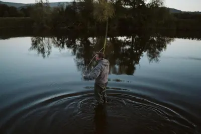 a man standing in the water holding a stick at River Cottage by Birch Stays in Glasbury