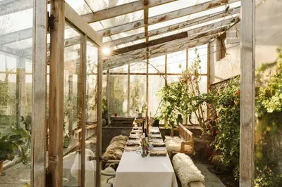 a long table in a greenhouse with plants at River Cottage by Birch Stays in Glasbury