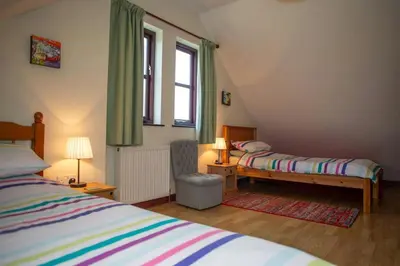 a bedroom with two beds and a desk and a window at Tan-yr-Onnen Llangrannog in New Quay