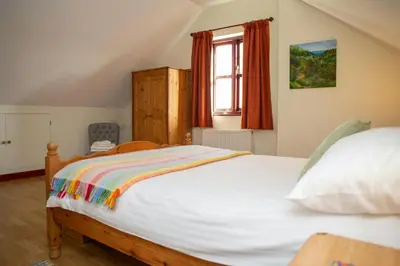a bedroom with a large white bed with a window at Tan-yr-Onnen Llangrannog in New Quay