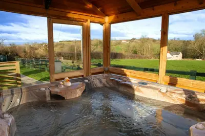 a hot tub in the middle of a large wooden house at Tan-yr-Onnen Llangrannog in New Quay