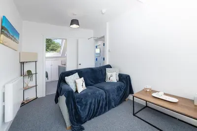 a living room with a blue couch and a table at Aberdovey Sea View Apartment in Aberdyfi