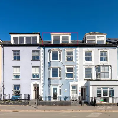 a large white building with windows on a street at Aberdovey Sea View Apartment in Aberdyfi