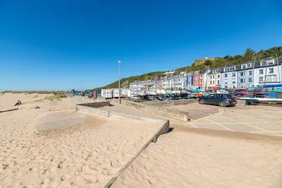 a sandy beach with buildings and a parking lot at Aberdovey Sea View Apartment in Aberdyfi