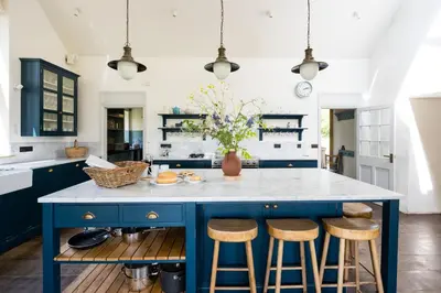 a kitchen with a blue island with bar stools at Welsh Border Escape- Perfect for families & groups in Clyro
